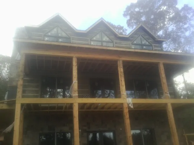 Dormers and porch framing on a large log home under construction — Roof Coating work by our crew in Kodak