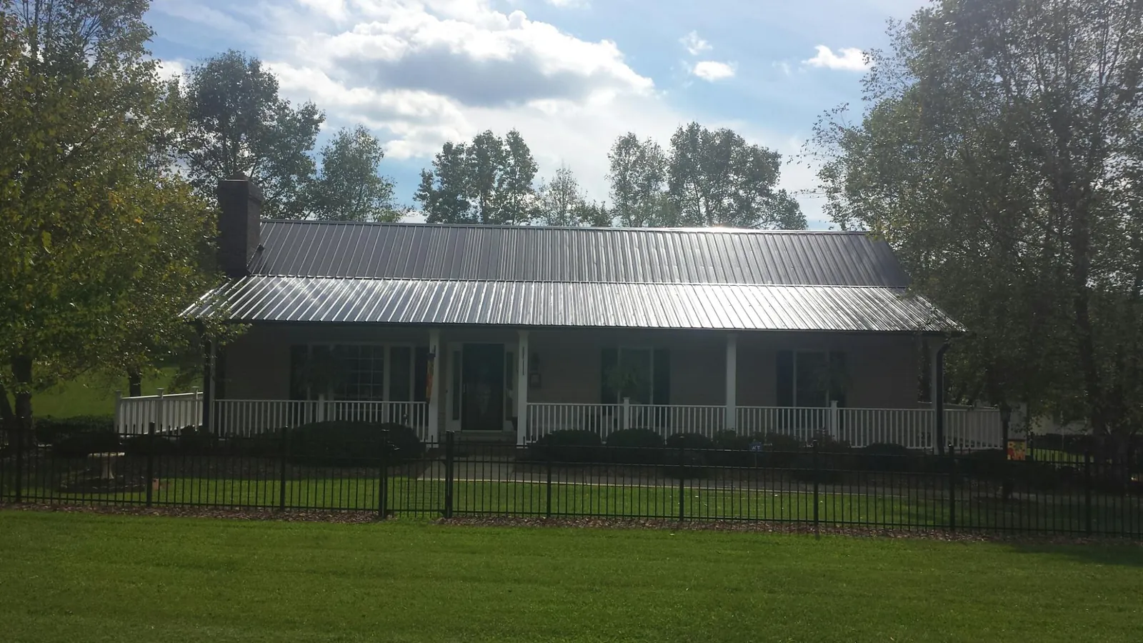 Gray metal roof on a brick ranch with a full width front porch — Gutter Guard Installation work by our crew in Kodak