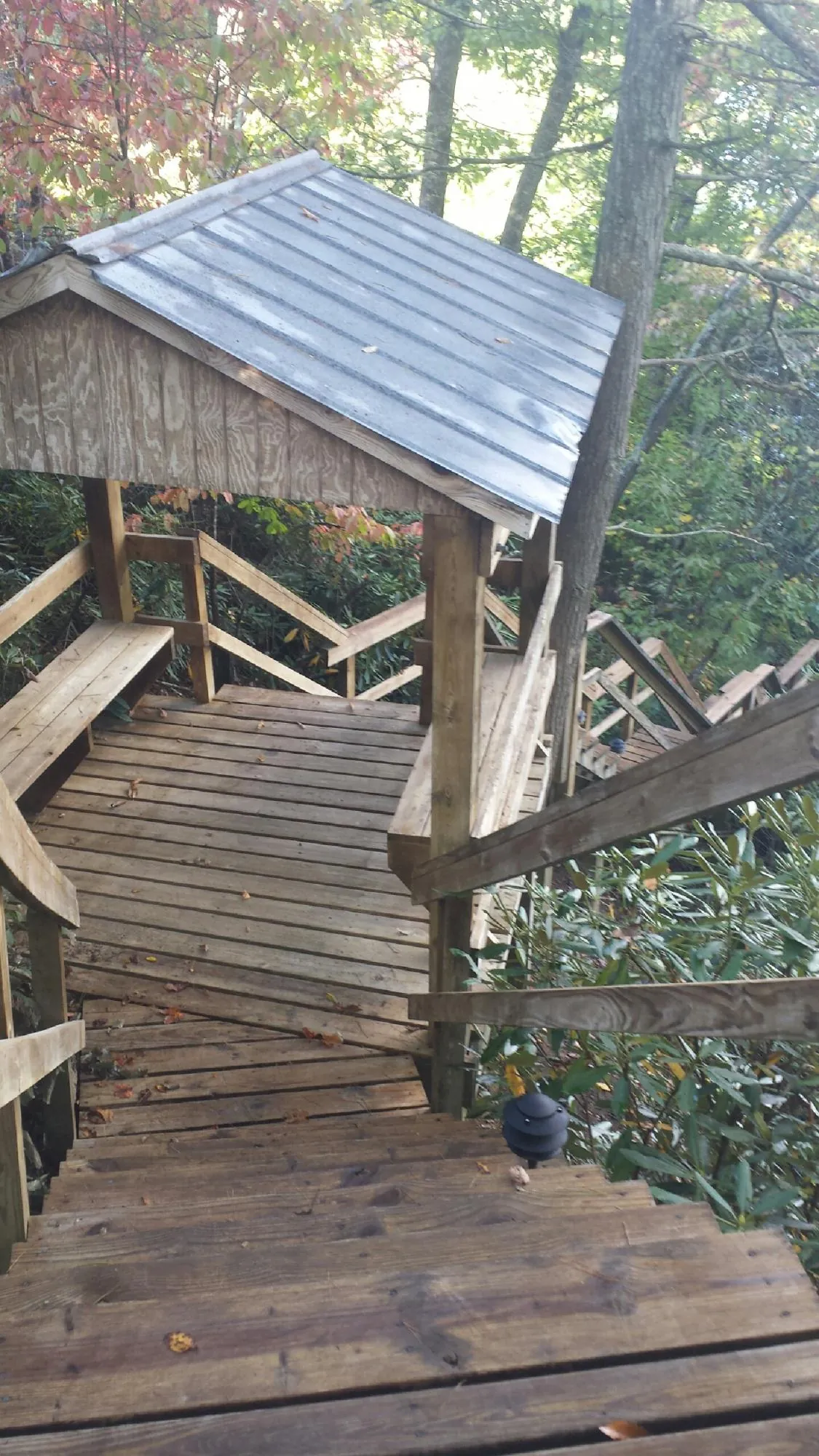 Metal roofed shelter over wooden steps on a wooded walkway — Skylight Repair & Installation work by our crew in Kodak