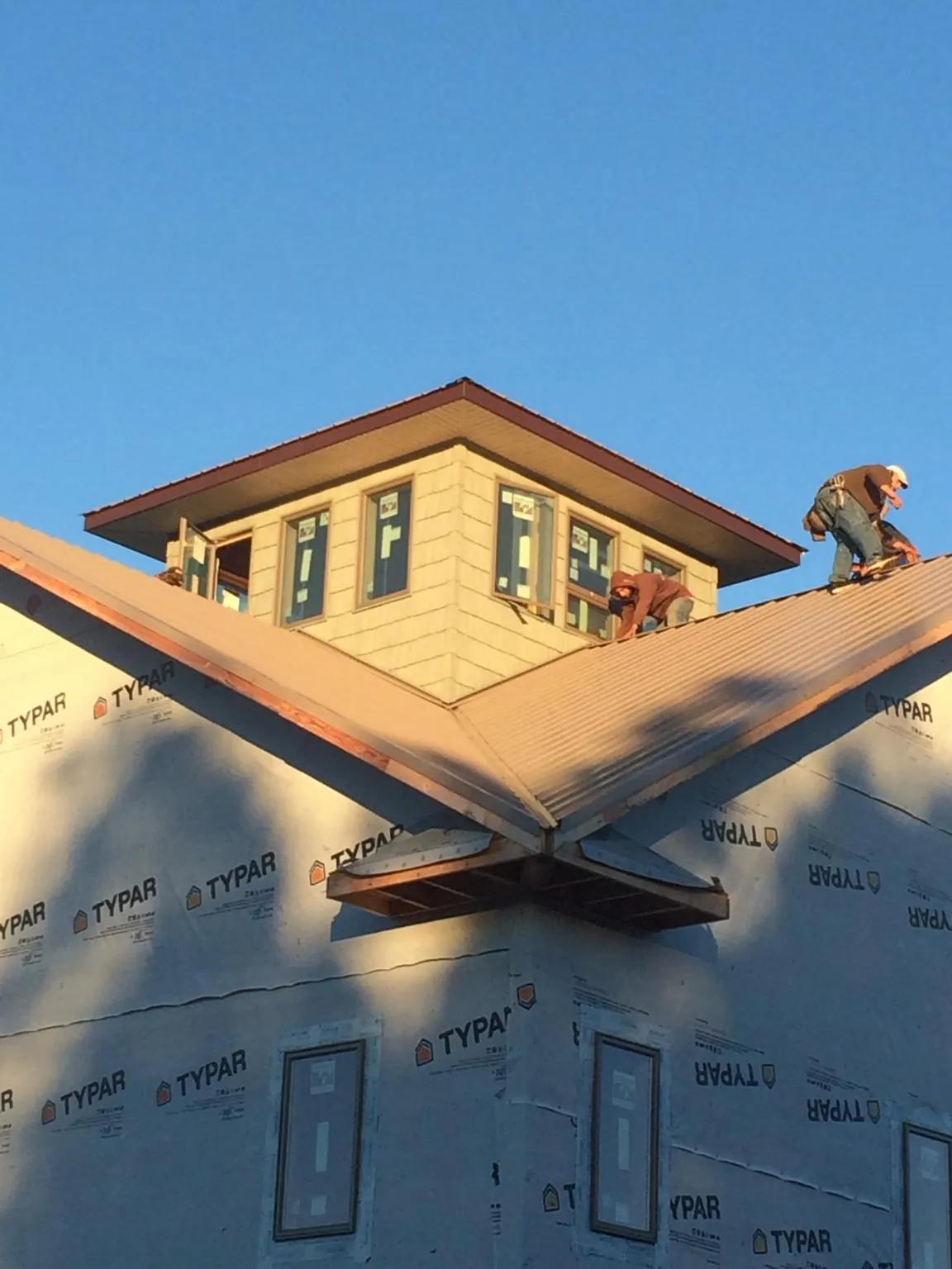 Roofers working around a rooftop cupola on a new metal roof at sunset — Roof Waterproofing in Kodak by Roofing Brothers